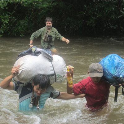 Rob Timmins (rear) and team members cross a rain-swollen stream in the Nakai-Nam Theun National Protected Area.(Photo courtesy Simeuang Phitsanoukan and WMPA)